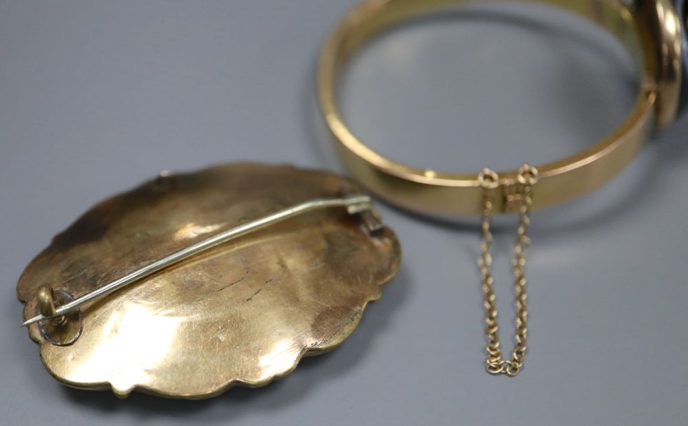 An early 20th century yellow metal (stamped 15) and banded agate set hinged bangle (repaired) and a Victorian mourning brooch.